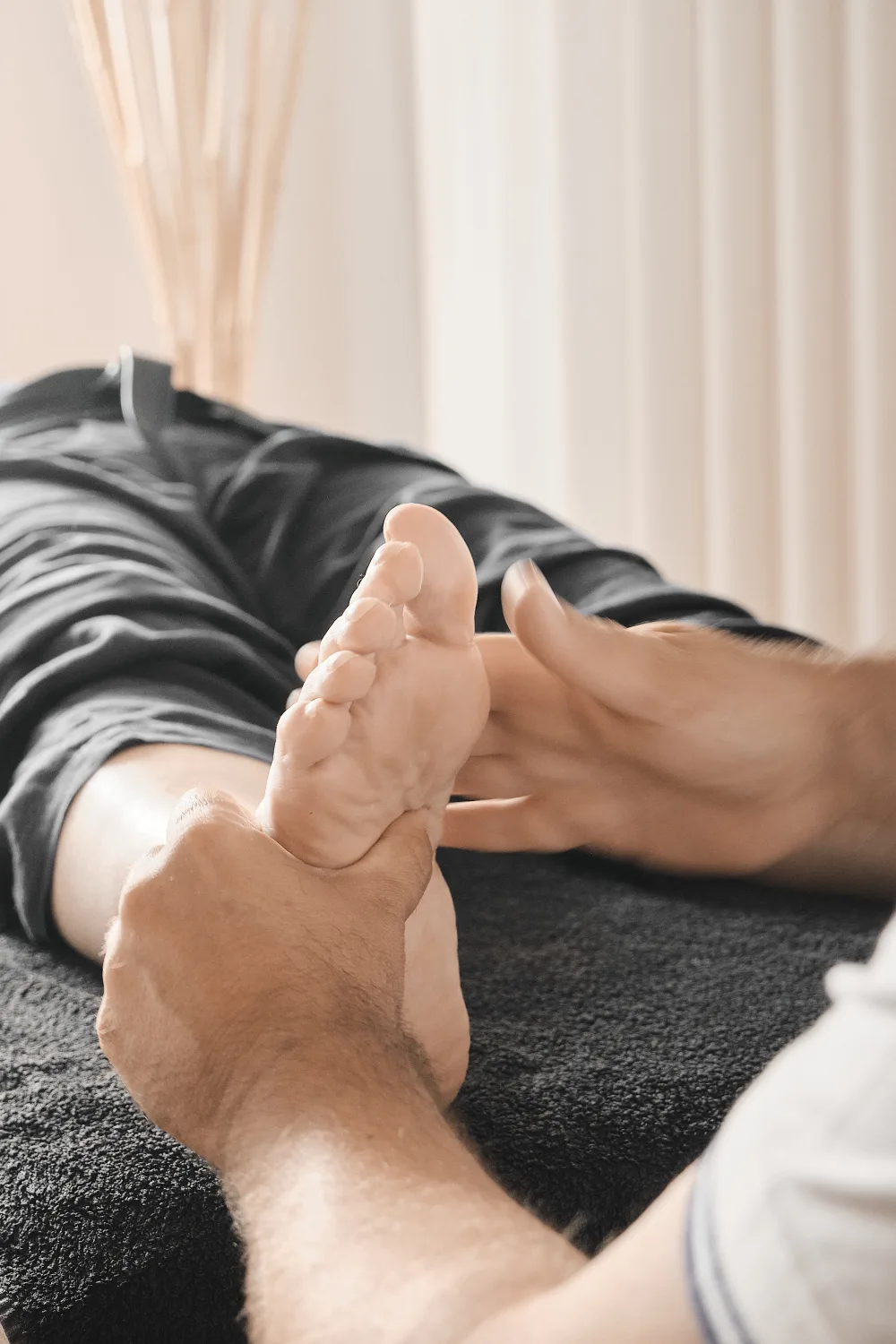 Una mano che avvolge il tallone di un piede, la persona distesa